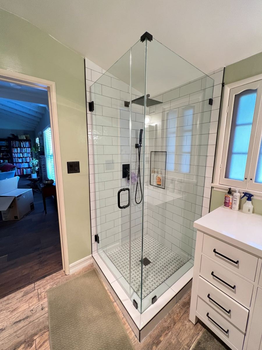 Corner glass shower with white subway tile and black hardware