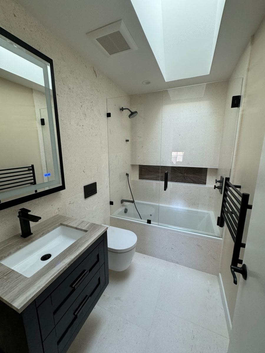 Remodeled bathroom with skylight, floating vanity and matte black fixtures